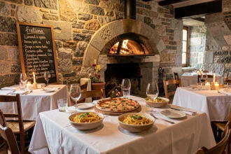 Salle de restaurant italien en Bretagne avec murs en pierre, tables en bois dressées et plats italiens traditionnels